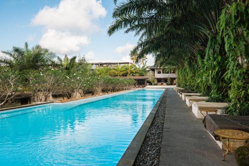 a swimming pool with blue water and palm trees at ONYX PARK RESORT Ubud in Ubud