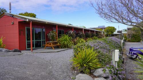 a red house with a table and flowers in front of it at Alpine-Pacific Holiday Park in Kaikoura