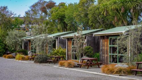 a group of picnic tables in front of a building at Alpine-Pacific Holiday Park in Kaikoura