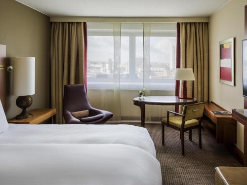 a hotel room with a bed and a table and chair at Pullman Cologne in Cologne