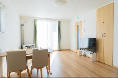 a dining room with a table and a television at Niseko Yu Villa A in Niseko