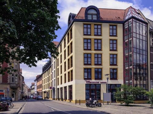 a yellow building with a red roof on a street at Mercure Hotel Erfurt Altstadt in Erfurt
