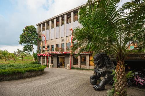 ONYX PARK RESORT Ubud في أوبود: تمثال امام عماره فيها نخله