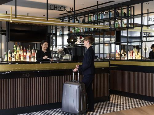 a man standing in front of a bar with a suitcase at Mercure Neu-Isenburg in Neu Isenburg