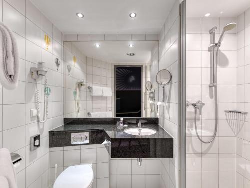 a bathroom with a toilet and a sink and a shower at Mercure Neu-Isenburg in Neu Isenburg