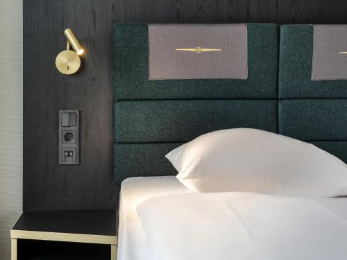 a bedroom with a white bed with a green headboard at Mercure Neu-Isenburg in Neu Isenburg