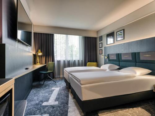 a hotel room with two beds and a tv at Mercure Neu-Isenburg in Neu Isenburg