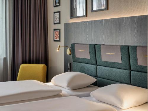 a hotel room with two beds and a chair at Mercure Neu-Isenburg in Neu Isenburg