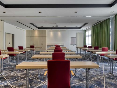 an empty classroom with desks and red chairs at Mercure Neu-Isenburg in Neu Isenburg