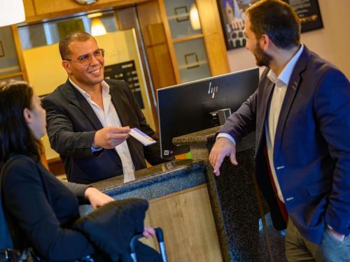a man standing at a phone booth with a customer at Novotel Freiburg am Konzerthaus in Freiburg im Breisgau