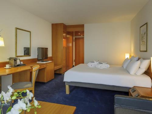 a hotel room with two beds and a desk at Novotel Freiburg am Konzerthaus in Freiburg im Breisgau