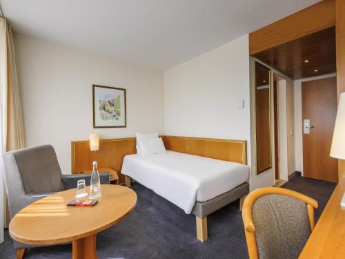 a hotel room with a bed and a table and a chair at Novotel Freiburg am Konzerthaus in Freiburg im Breisgau