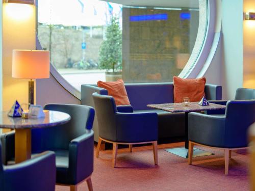 a waiting room with chairs and tables and a slide at Novotel Freiburg am Konzerthaus in Freiburg im Breisgau