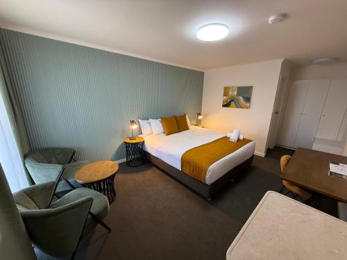 a hotel room with a bed and a table and chairs at Mid City Motel Warrnambool in Warrnambool