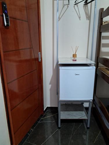 a small refrigerator in a room with a door at Suite Família a 10min do aeroporto in Guarulhos