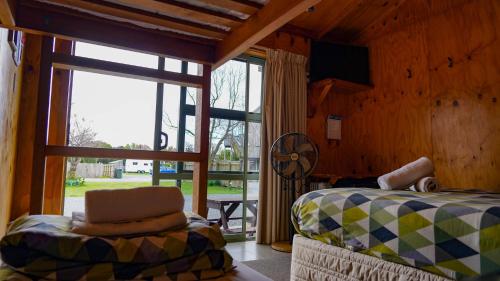 a bedroom with a bed and a chair and a window at Alpine-Pacific Holiday Park in Kaikoura