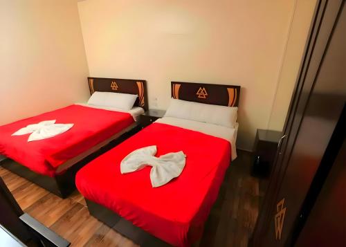 two beds in a room with red sheets at Pyramids Sphinx VIEW Hotel in Cairo