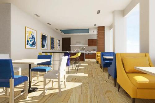 a dining room with blue and yellow chairs and tables at Hotel Plaza Cascadas in Tegucigalpa