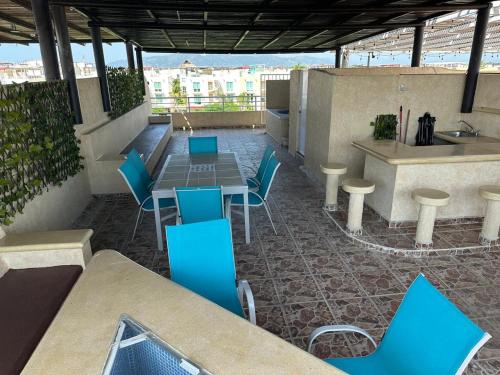 a patio with blue chairs and a table and a counter at Departamento zona Diamante in Acapulco