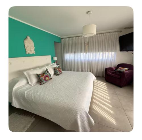 a bedroom with a white bed and a red chair at Acantilados mar y pileta in Mar del Plata