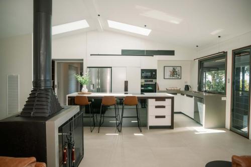 a kitchen with a stove and some chairs in it at Maleny Scenic Retreat in Booroobin