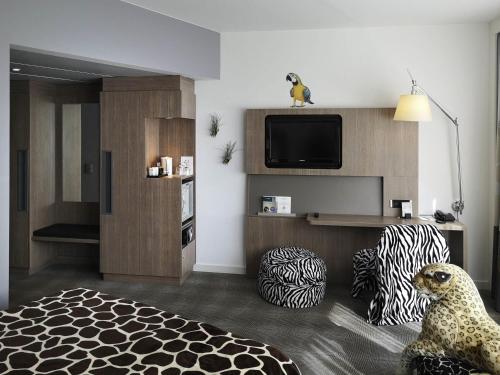 a living room with a tv and a living room with a couch at Novotel Hannover in Hannover