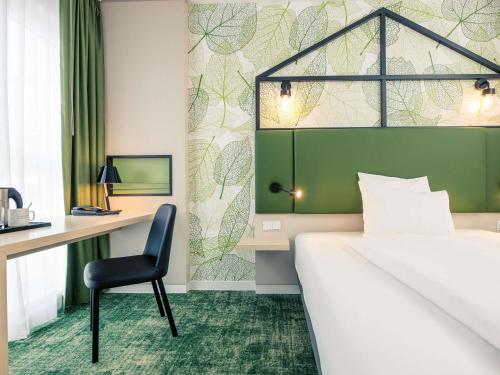 a bedroom with a bed and a desk and a chair at Mercure Hotel Hannover Mitte in Hannover
