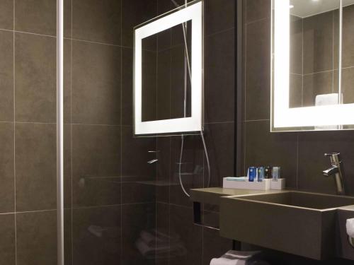 a bathroom with a shower and a sink and a mirror at Novotel Hannover in Hannover