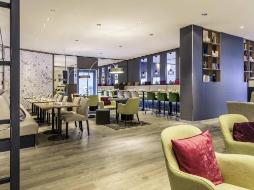 a restaurant with tables and chairs and a bar at Mercure Hotel Hannover Mitte in Hannover