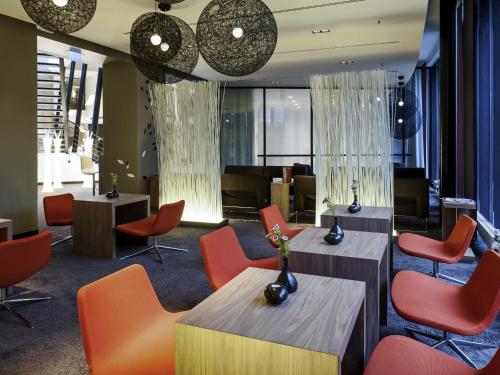 a waiting room with orange chairs and tables at Novotel Hannover in Hannover