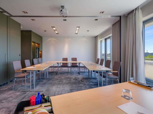 a conference room with long tables and chairs at Mercure Hotel Hannover Mitte in Hannover