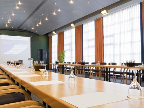 a conference room with a long table and chairs at Novotel Hannover in Hannover