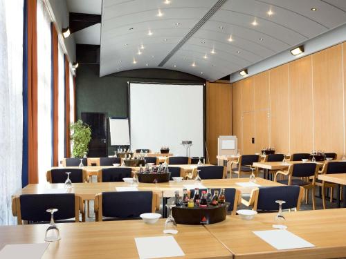 a conference room with tables and chairs and a whiteboard at Novotel Hannover in Hannover
