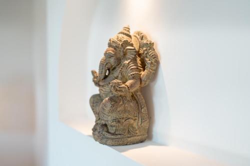 a statue sitting on a white wall at Rumah Kita Ecolodge in Ubud