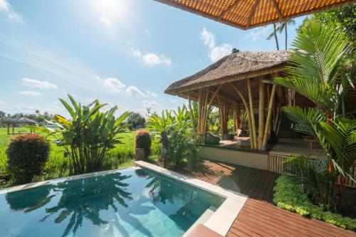a resort with a swimming pool and a hut at Rumah Kita Ecolodge in Ubud