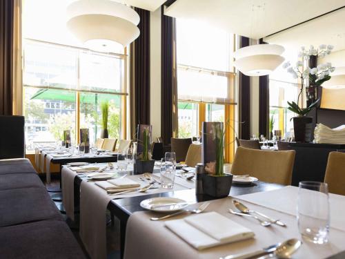 a dining room with tables and chairs and windows at Novotel Karlsruhe City in Karlsruhe