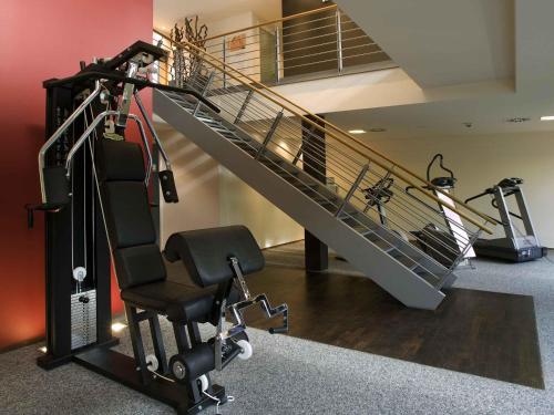 a gym with a staircase and a chair and treadmill at Novotel Karlsruhe City in Karlsruhe