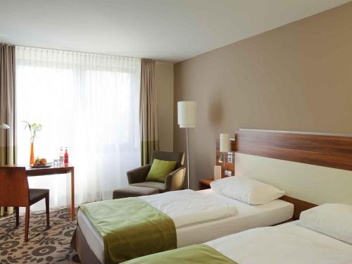 a hotel room with two beds and a chair at Mercure Tagungs- & Landhotel Krefeld in Krefeld