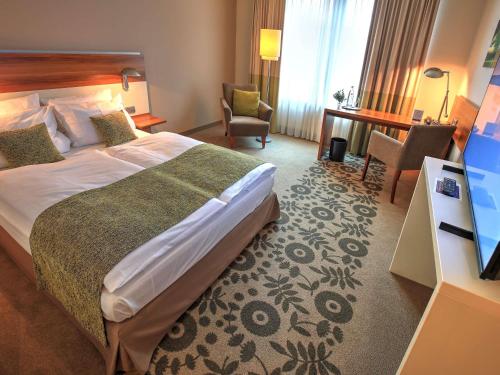 a hotel room with a large bed and a desk at Mercure Tagungs- & Landhotel Krefeld in Krefeld
