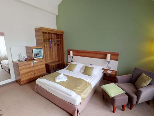 a bedroom with a large bed and a chair at Mercure Tagungs- & Landhotel Krefeld in Krefeld