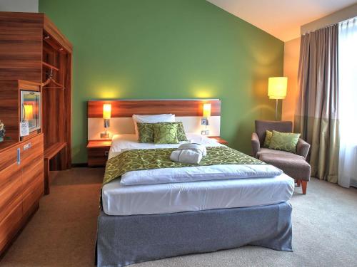 a hotel room with a large bed and a chair at Mercure Tagungs- & Landhotel Krefeld in Krefeld