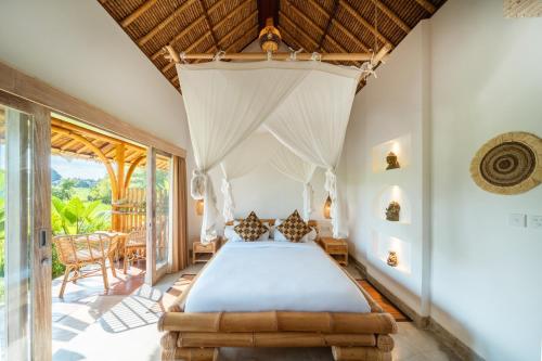 a bedroom with a bed and a large window at Rumah Kita Ecolodge in Ubud