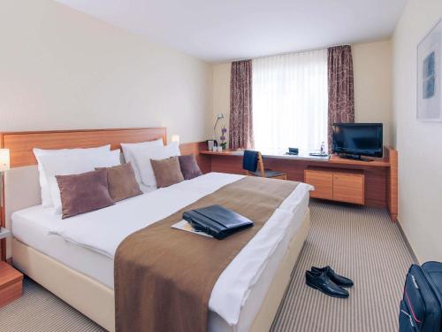a hotel room with a large bed and a television at Mercure Hotel Mannheim am Rathaus in Mannheim
