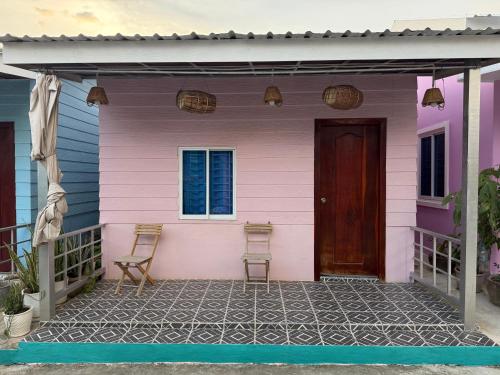 a pink house with two chairs and a door at Lazy Mango Home Stay in Phumĭ Poŭthĭ Mâ Srei