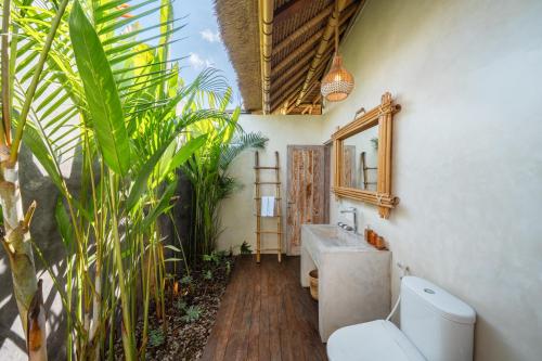 a bathroom with a sink and a toilet and a mirror at Rumah Kita Ecolodge in Ubud