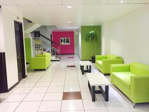 a waiting room with green and pink chairs and tables at Hotel Plazha in Tuxtla Gutiérrez
