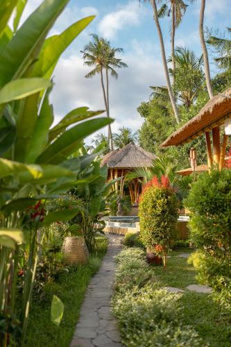 a path leading to a resort with palm trees at Rumah Kita Ecolodge in Ubud