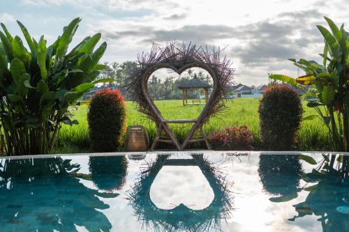 a garden with a heart shapediary next to a pool at Rumah Kita Ecolodge in Ubud
