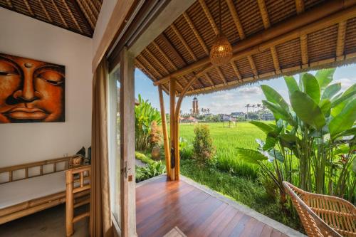 an open door to a patio with a view of a field at Rumah Kita Ecolodge in Ubud