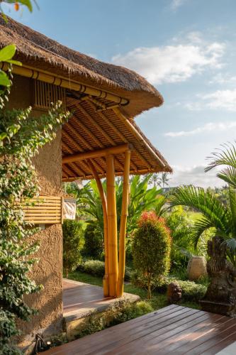 a wooden pergola on the side of a building at Rumah Kita Ecolodge in Ubud